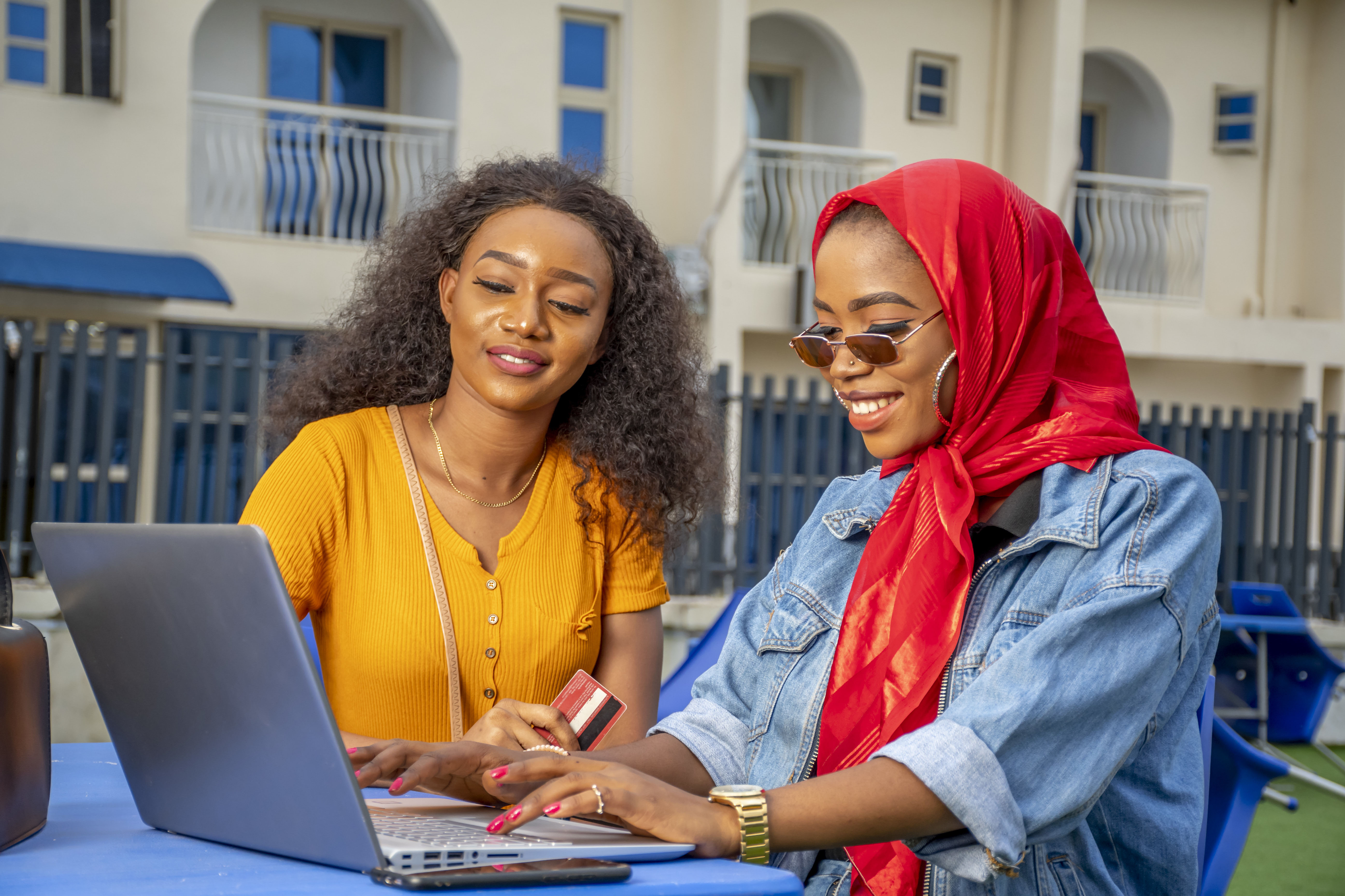 Two African females shopping online while sitting in a cafe