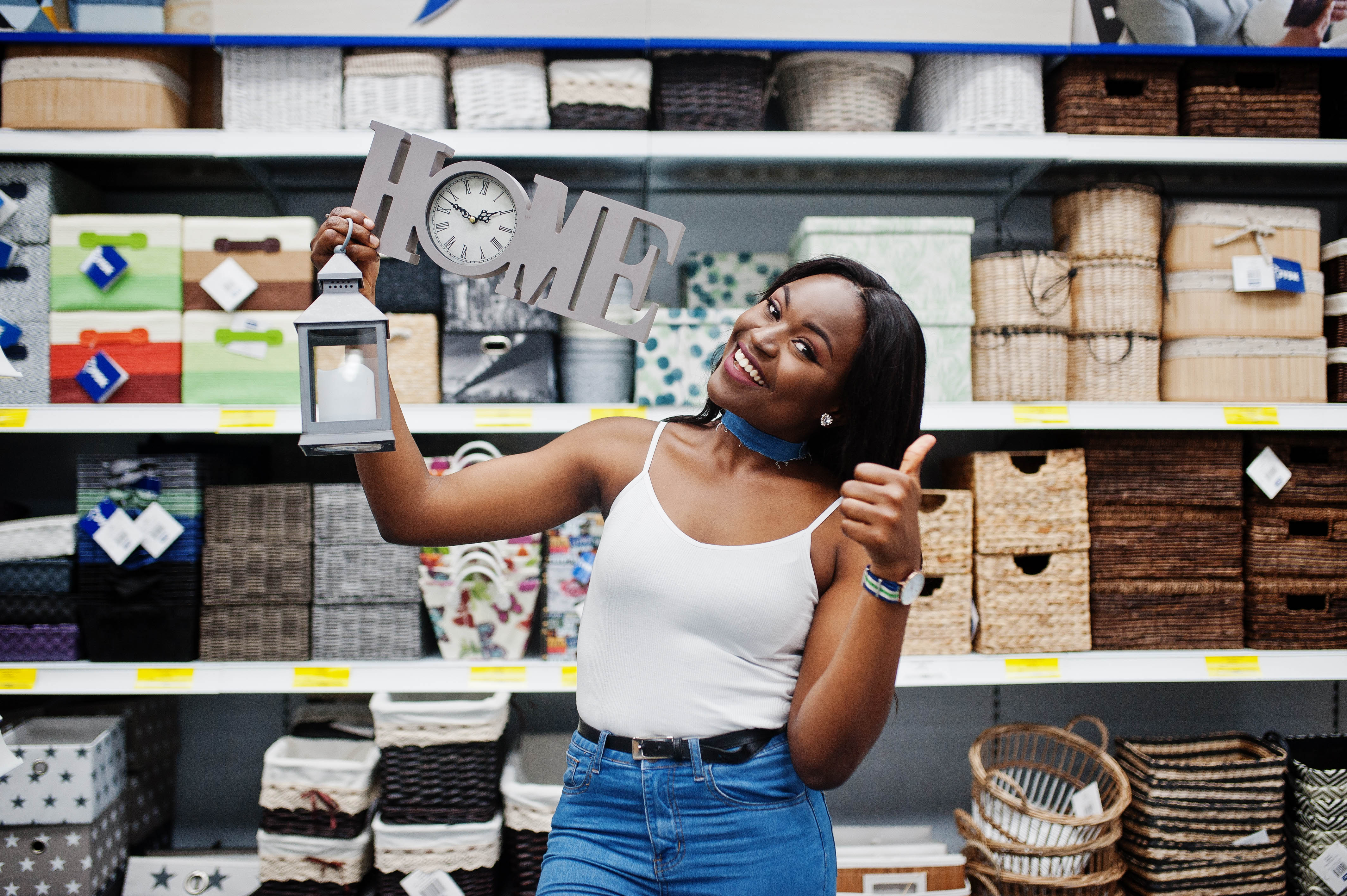 Portrait of a beautiful african american woman holding home sign and a sconce torch in the store.